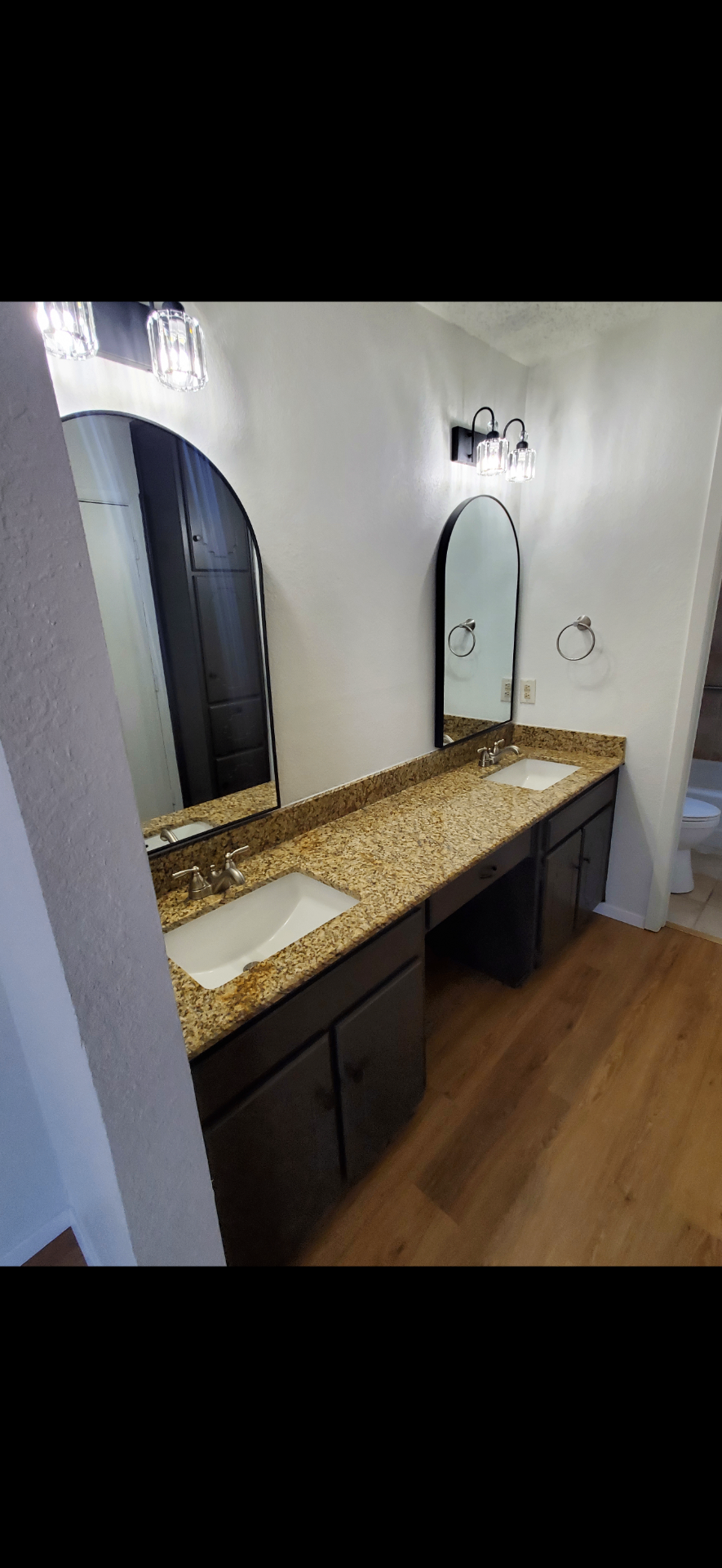 Bathroom with double granite vanity and arched mirrors