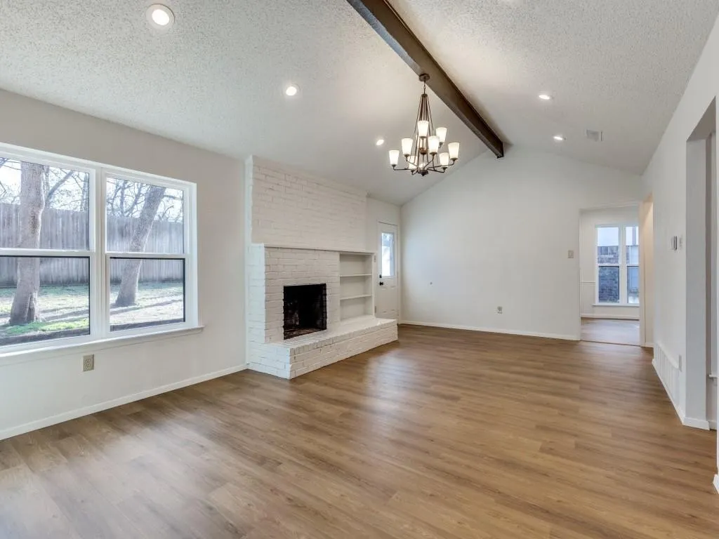 Vaulted living room with white brick fireplace and new flooring